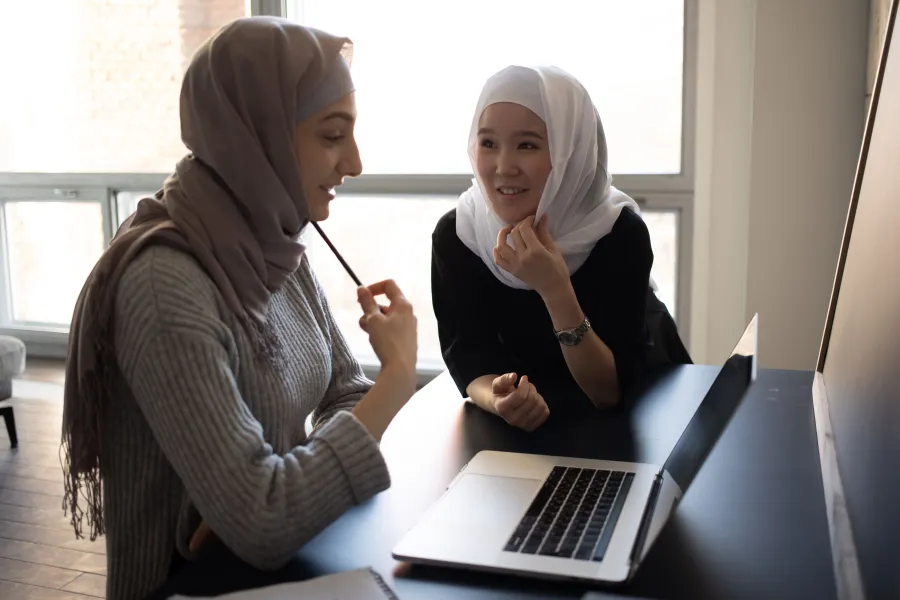 Deux étudiantes échangent devant un ordinateur portable