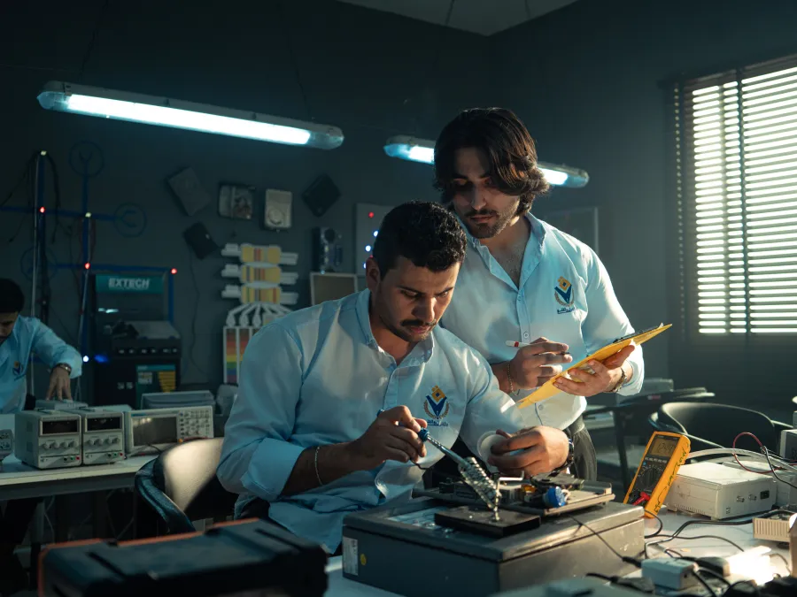Techniciens en atelier de maintenance électronique avec instruments de mesure